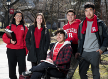 Students in Rutgers gear standing next to a bench.